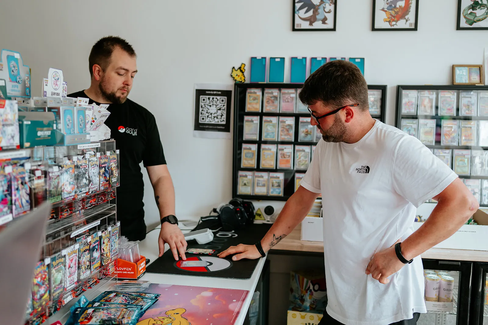 Staff discussing a trade-in card at the counter at Card Guys